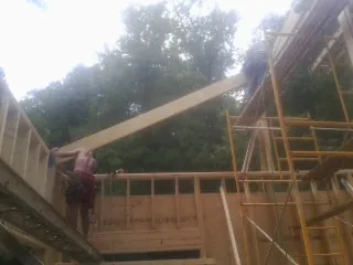 Carpenter raising a rafter beam on a new second story frame in Centralia