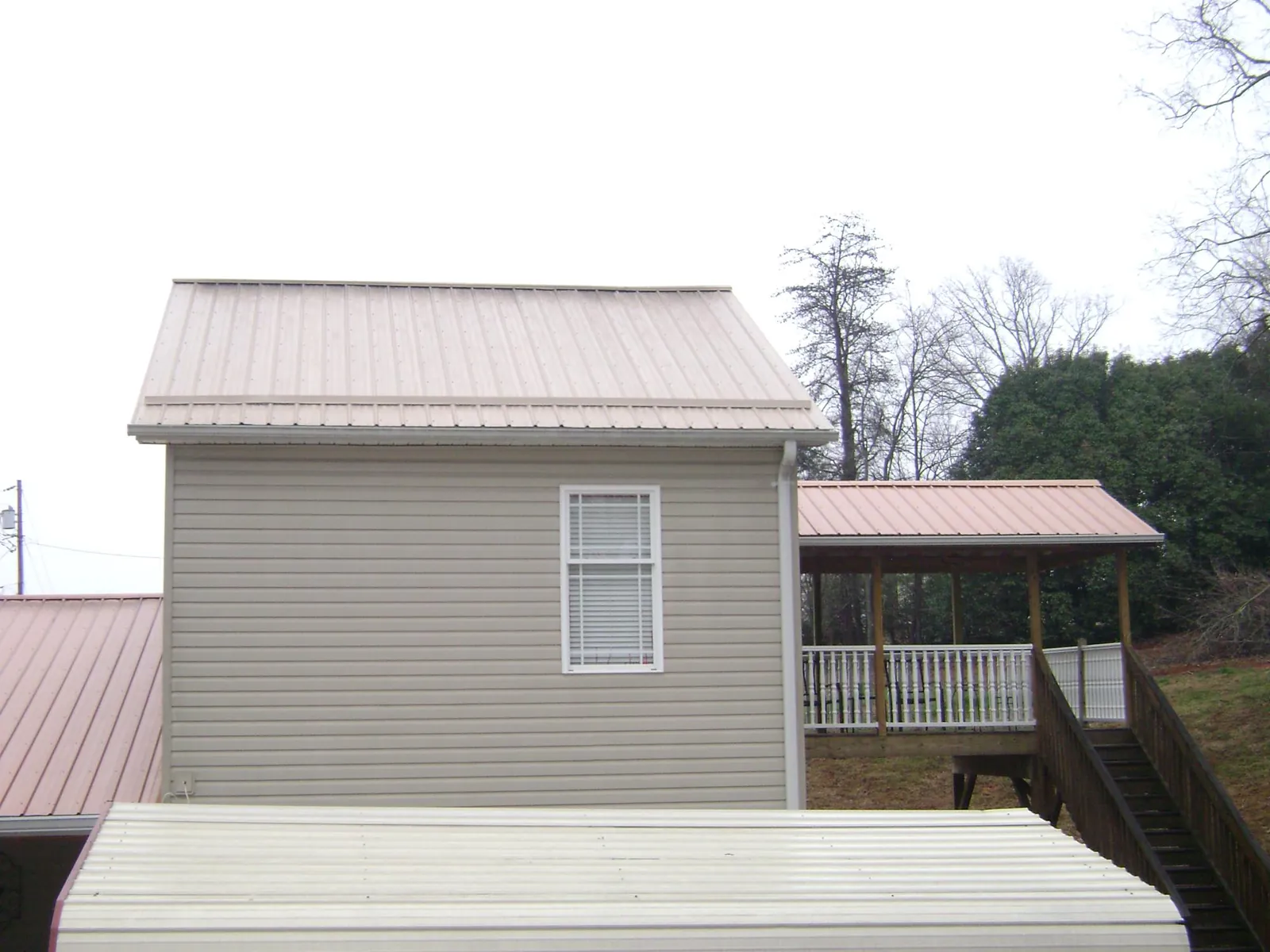Tan metal roofs on a two story addition and attached porch, from a Roof Replacement job in Centralia